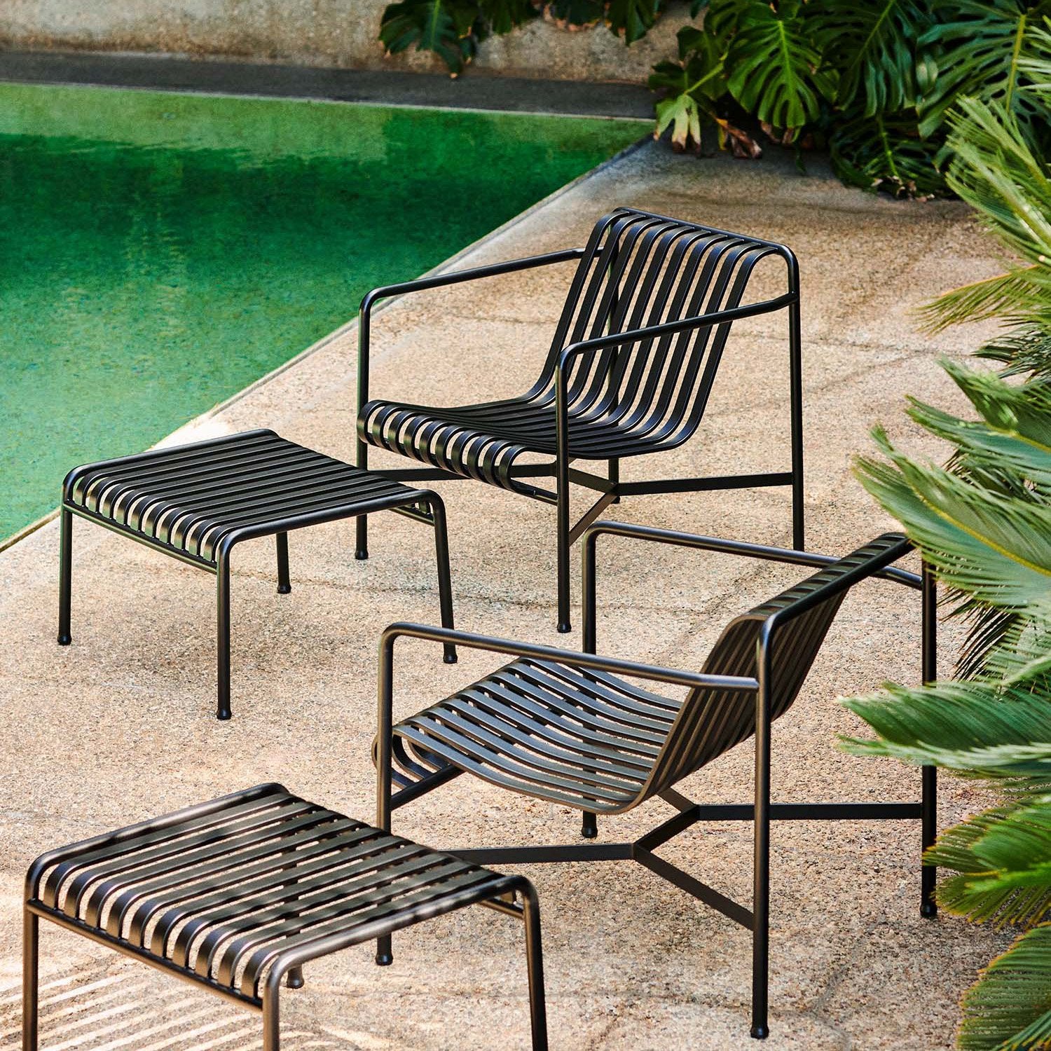 HAY Palissade Low Lounge Chair Olive in an outdoor setting near a pool with tropical plants.